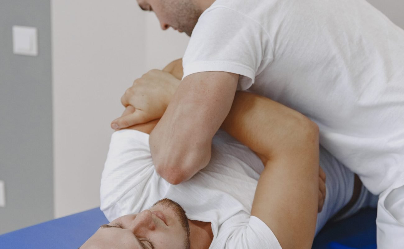 Man in the medical office. Physiotherapist is rehabilitating back.